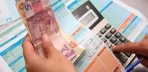 Uma mulher segura uma conta de luz enquanto digita em uma calculadora